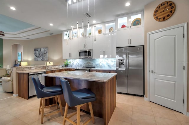 kitchen with a kitchen breakfast bar, white cabinets, stainless steel appliances, and kitchen peninsula