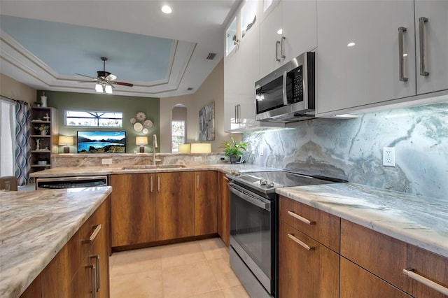 kitchen featuring appliances with stainless steel finishes, decorative backsplash, a raised ceiling, sink, and white cabinetry