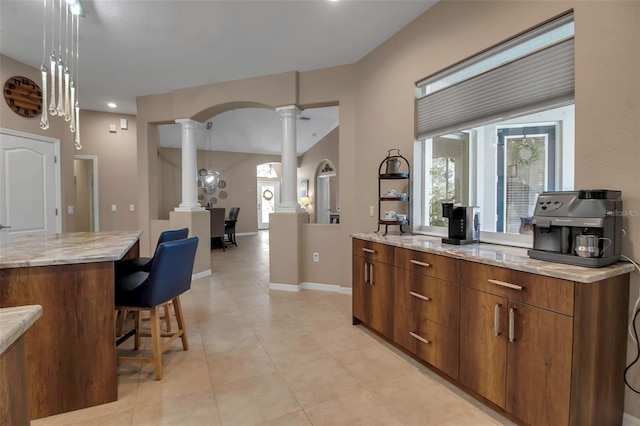 kitchen with ornate columns, a center island, a healthy amount of sunlight, and decorative light fixtures