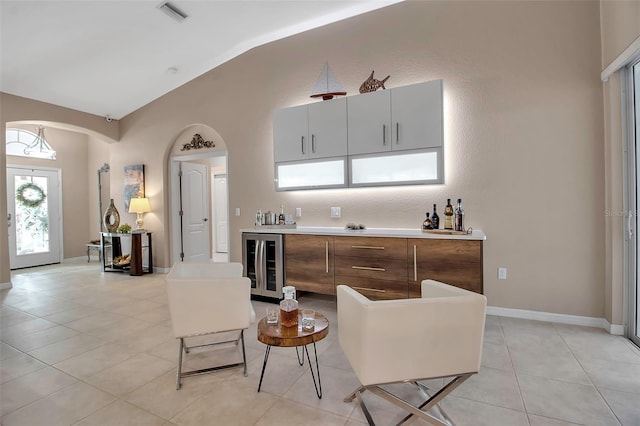 kitchen with light tile patterned floors, vaulted ceiling, and beverage cooler