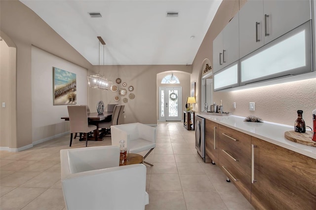 kitchen featuring vaulted ceiling, hanging light fixtures, decorative backsplash, and light tile patterned floors