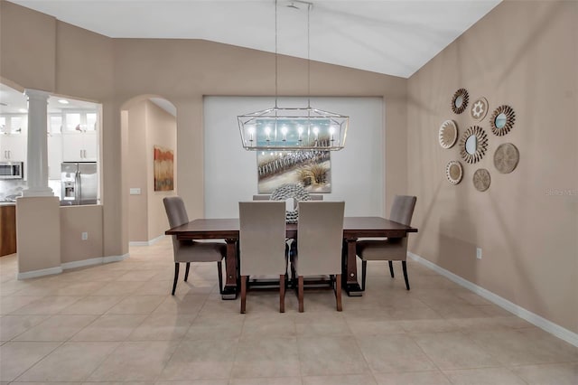 dining room featuring light tile patterned floors, vaulted ceiling, and ornate columns