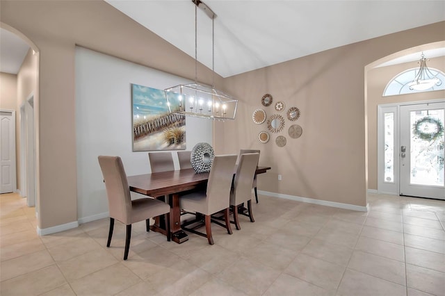 tiled dining space with lofted ceiling and a notable chandelier