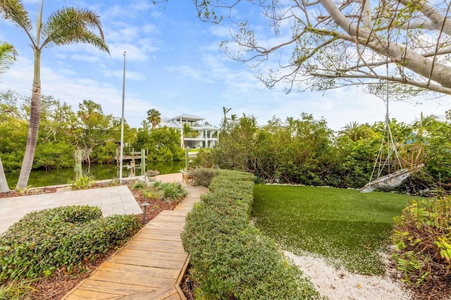 surrounding community featuring a boat dock, a water view, and a lawn