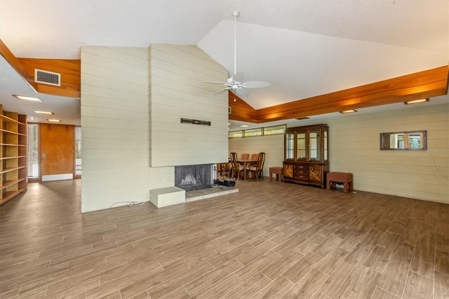 unfurnished living room with a multi sided fireplace, vaulted ceiling, ceiling fan, and wooden walls