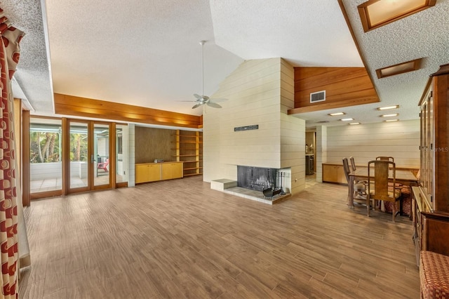 living room featuring a multi sided fireplace, wooden walls, vaulted ceiling, ceiling fan, and wood-type flooring