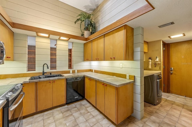 kitchen featuring sink, black dishwasher, tile countertops, washer / dryer, and electric stove