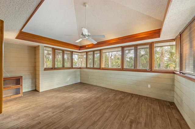 unfurnished sunroom with a tray ceiling, ceiling fan, and lofted ceiling