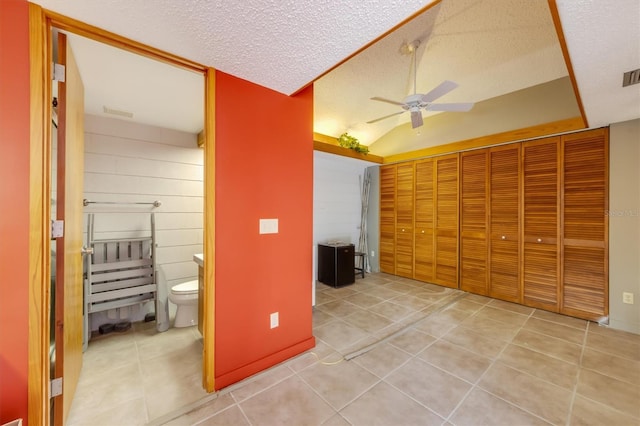 interior space with tile patterned floors, ceiling fan, lofted ceiling, and a textured ceiling