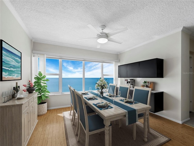 dining room featuring a textured ceiling, light hardwood / wood-style flooring, ceiling fan, and crown molding