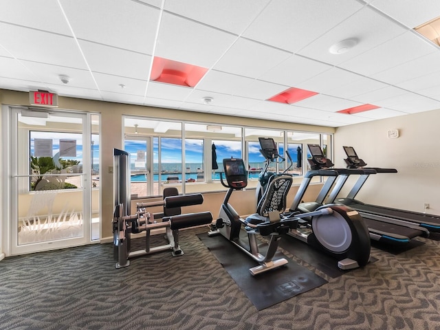 gym featuring carpet, a paneled ceiling, a water view, and a wealth of natural light