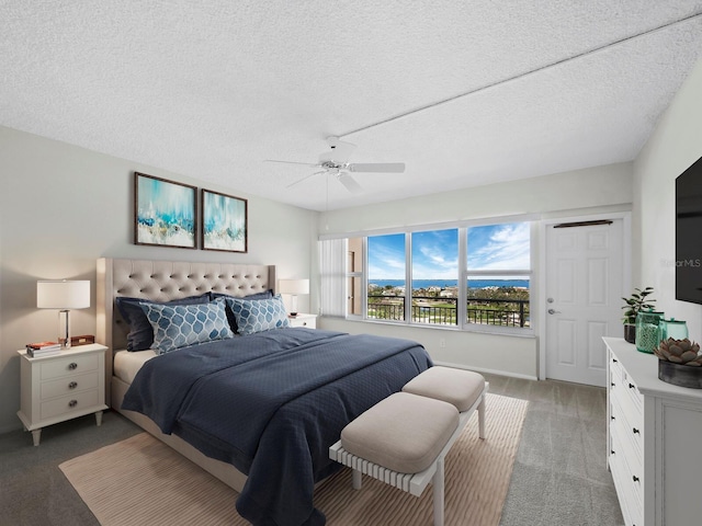 bedroom with a textured ceiling, dark carpet, and ceiling fan