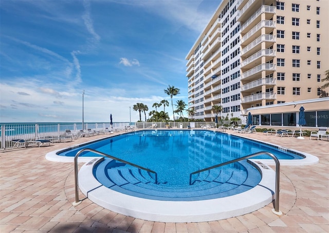 view of pool with a patio area and a water view