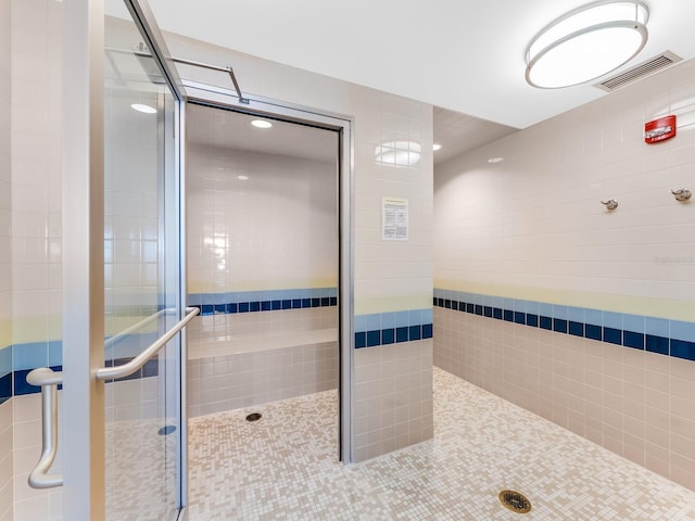 bathroom featuring tile patterned floors, an enclosed shower, and tile walls