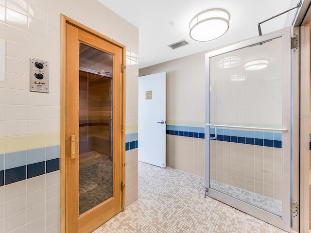 hallway with light tile patterned floors and tile walls