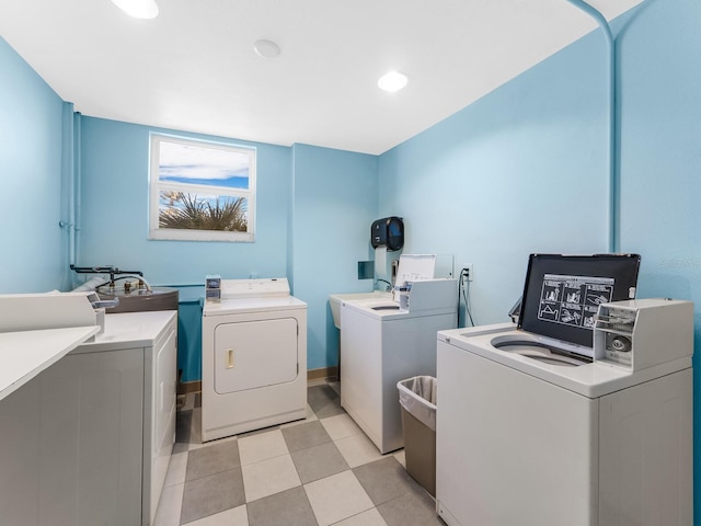 clothes washing area with washing machine and dryer, sink, and light tile patterned floors