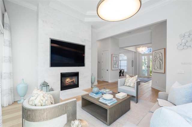 living room featuring a tile fireplace, hardwood / wood-style floors, and crown molding