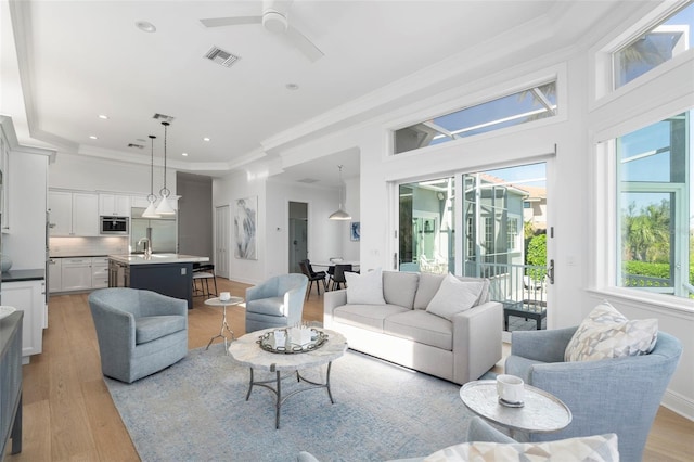 living room with crown molding, ceiling fan, sink, and light hardwood / wood-style floors