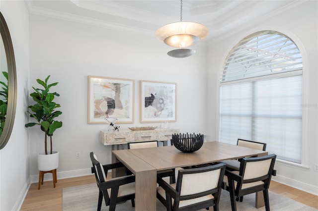 dining room featuring light hardwood / wood-style floors, crown molding, and a tray ceiling