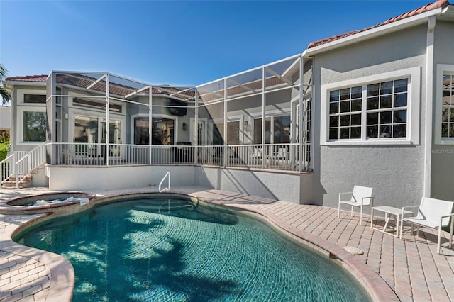 view of pool featuring glass enclosure, an in ground hot tub, and a patio area