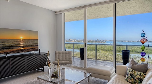 tiled living room featuring floor to ceiling windows and a water view