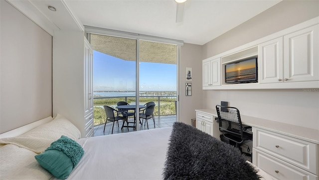 bedroom featuring ceiling fan, expansive windows, access to outside, and built in desk