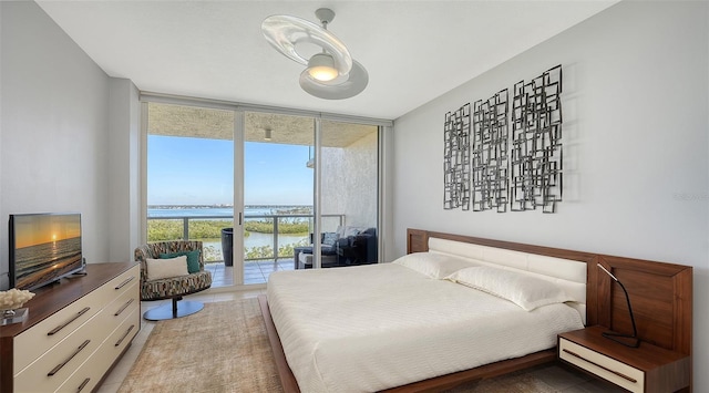 tiled bedroom featuring a water view, expansive windows, access to exterior, and multiple windows