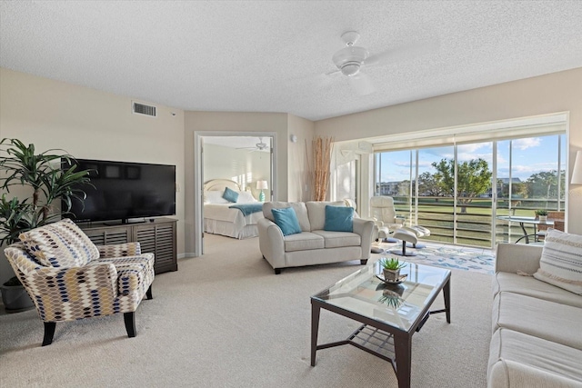 carpeted living room featuring ceiling fan and a textured ceiling