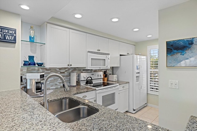 kitchen featuring white cabinetry, sink, light stone countertops, backsplash, and white appliances