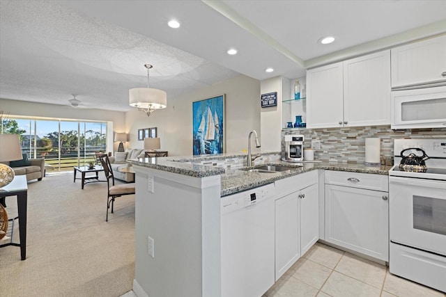 kitchen with kitchen peninsula, white appliances, sink, stone countertops, and white cabinetry