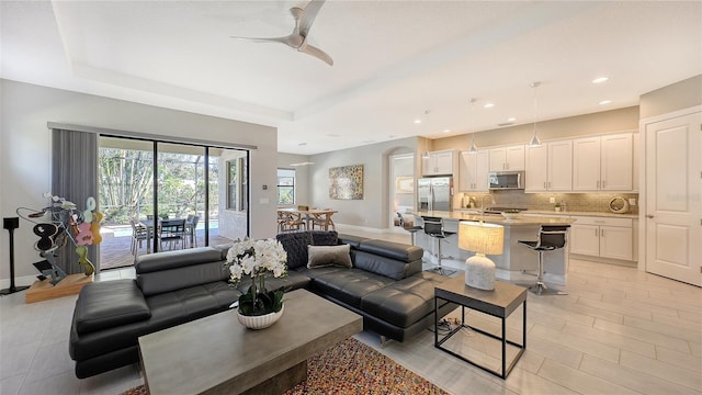 living room featuring a raised ceiling and ceiling fan