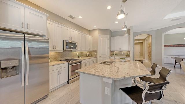 kitchen featuring white cabinetry, a kitchen island with sink, sink, and appliances with stainless steel finishes