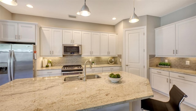 kitchen with stainless steel appliances, white cabinetry, light stone countertops, and hanging light fixtures