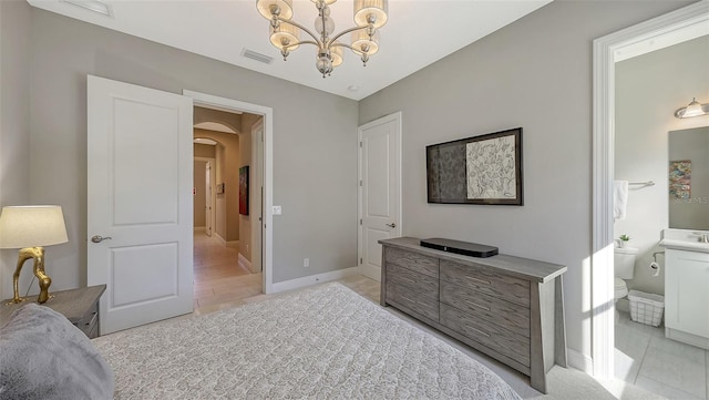 bedroom featuring light tile patterned flooring, an inviting chandelier, and ensuite bath