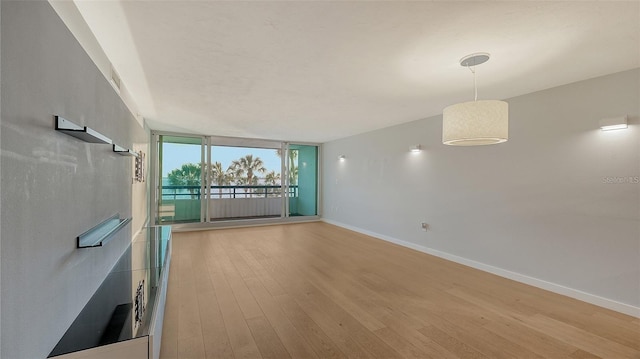 empty room featuring floor to ceiling windows and light wood-type flooring