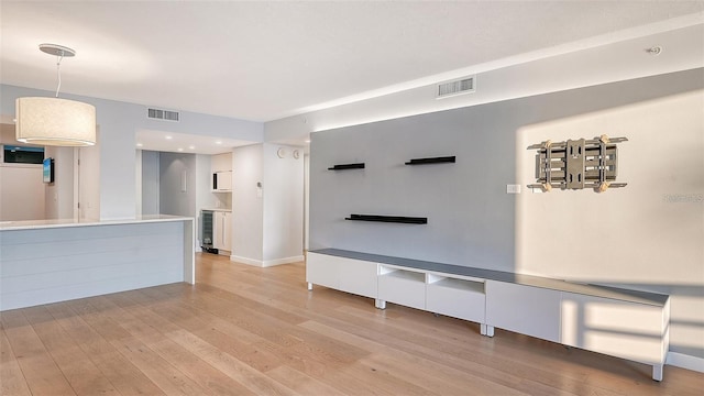 unfurnished living room featuring wine cooler and light hardwood / wood-style floors