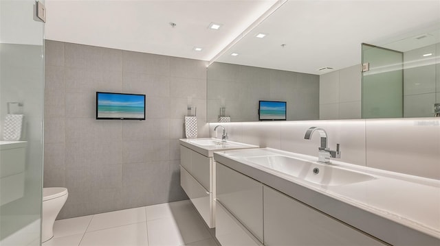 bathroom featuring tile patterned floors, vanity, tile walls, and toilet