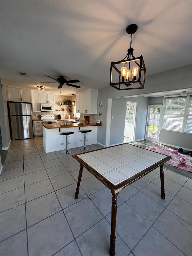 game room with ceiling fan with notable chandelier and light tile patterned flooring