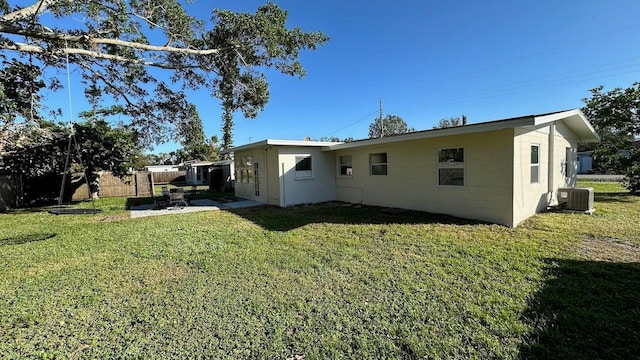 rear view of property featuring a yard and central air condition unit