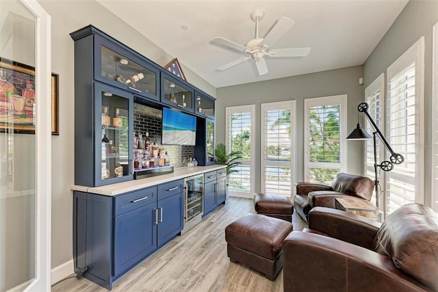 living room with light wood-type flooring, wine cooler, bar, and ceiling fan