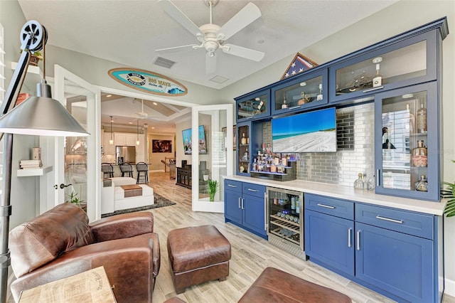 bar with ceiling fan, wine cooler, light hardwood / wood-style flooring, stainless steel refrigerator with ice dispenser, and blue cabinets