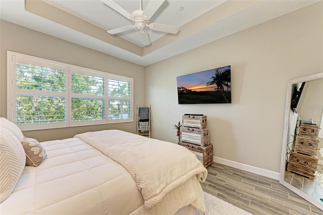 bedroom featuring a tray ceiling, ceiling fan, and hardwood / wood-style floors