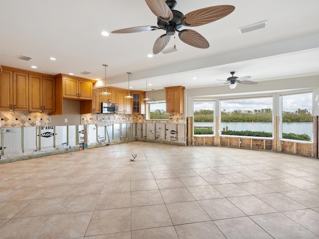 interior space with a water view, ceiling fan, and light tile patterned flooring