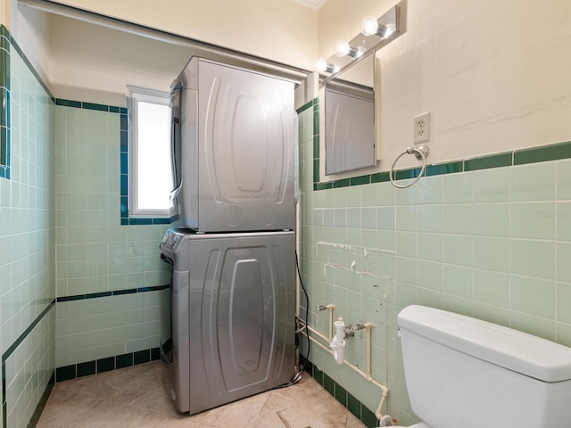 bathroom with tile patterned floors, toilet, tile walls, and stacked washer and clothes dryer