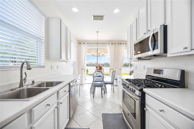 kitchen featuring white cabinetry, stainless steel appliances, sink, and hanging light fixtures