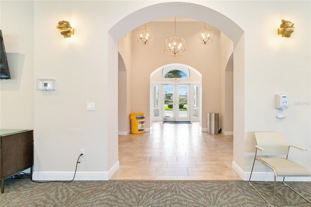 hallway featuring french doors, a notable chandelier, and light tile patterned floors