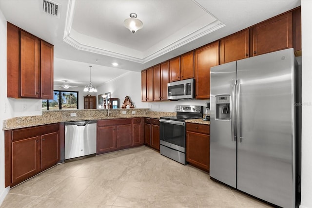 kitchen featuring hanging light fixtures, stainless steel appliances, kitchen peninsula, and a tray ceiling