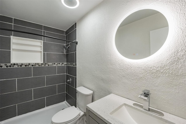 bathroom with vanity, toilet, and tiled shower