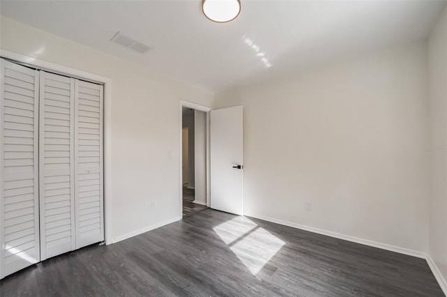 unfurnished bedroom featuring a closet and dark hardwood / wood-style flooring