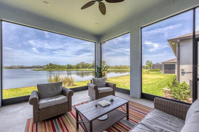 sunroom with ceiling fan and a water view